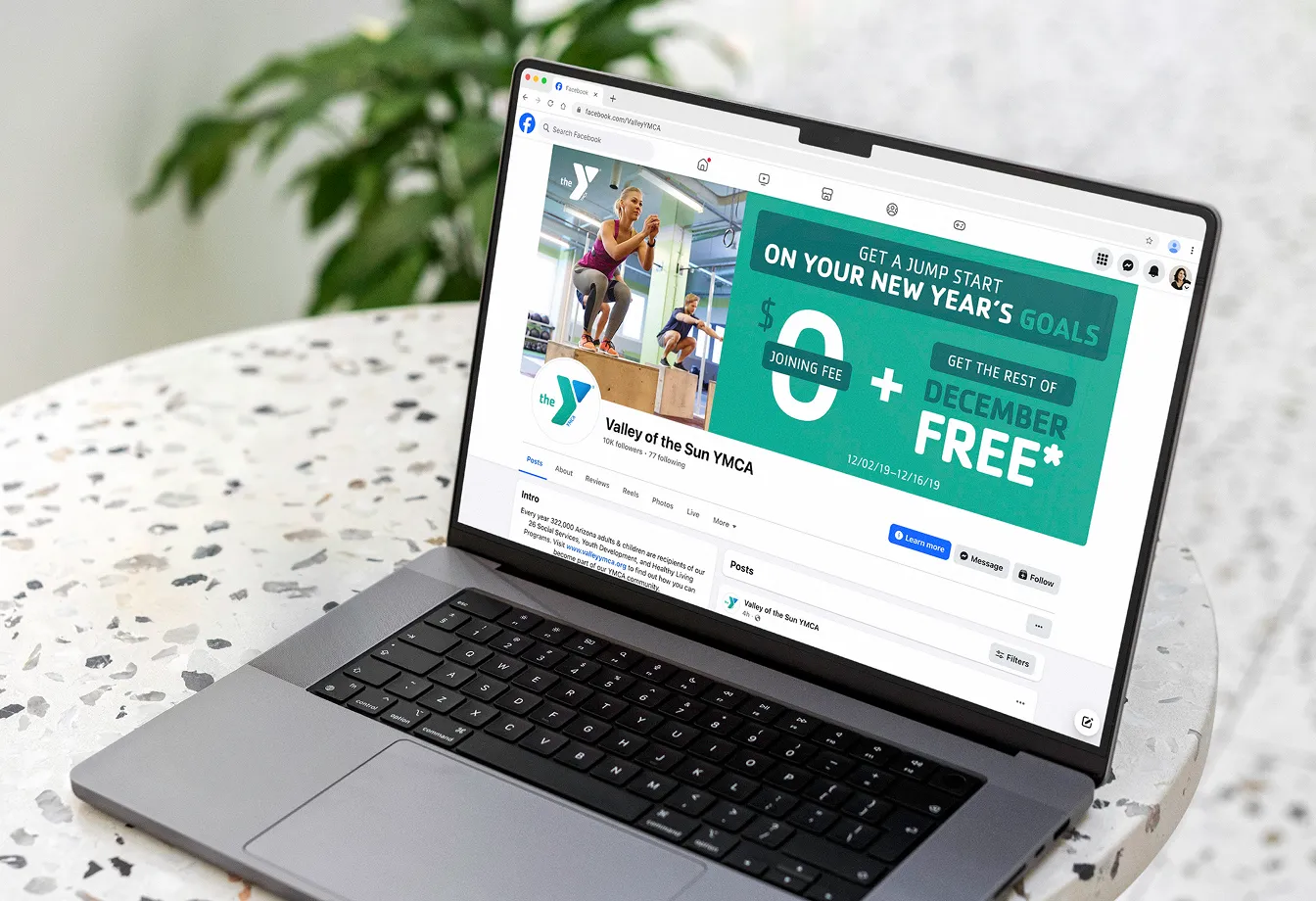 A laptop displaying a YMCA social post promoting the December free membership offer.