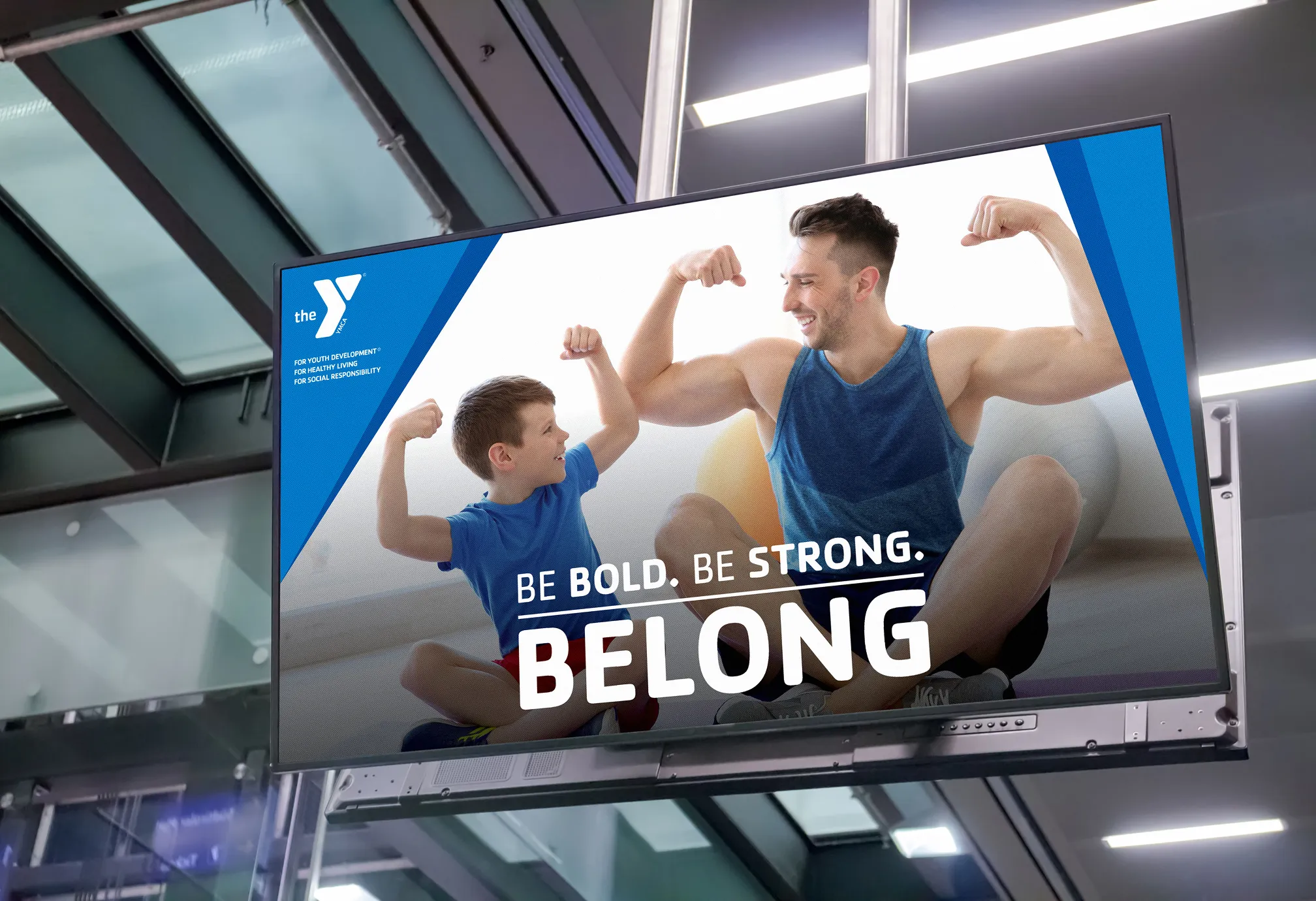 A screen showing a YMCA "Belong" advert with a man and a boy flexing together.
