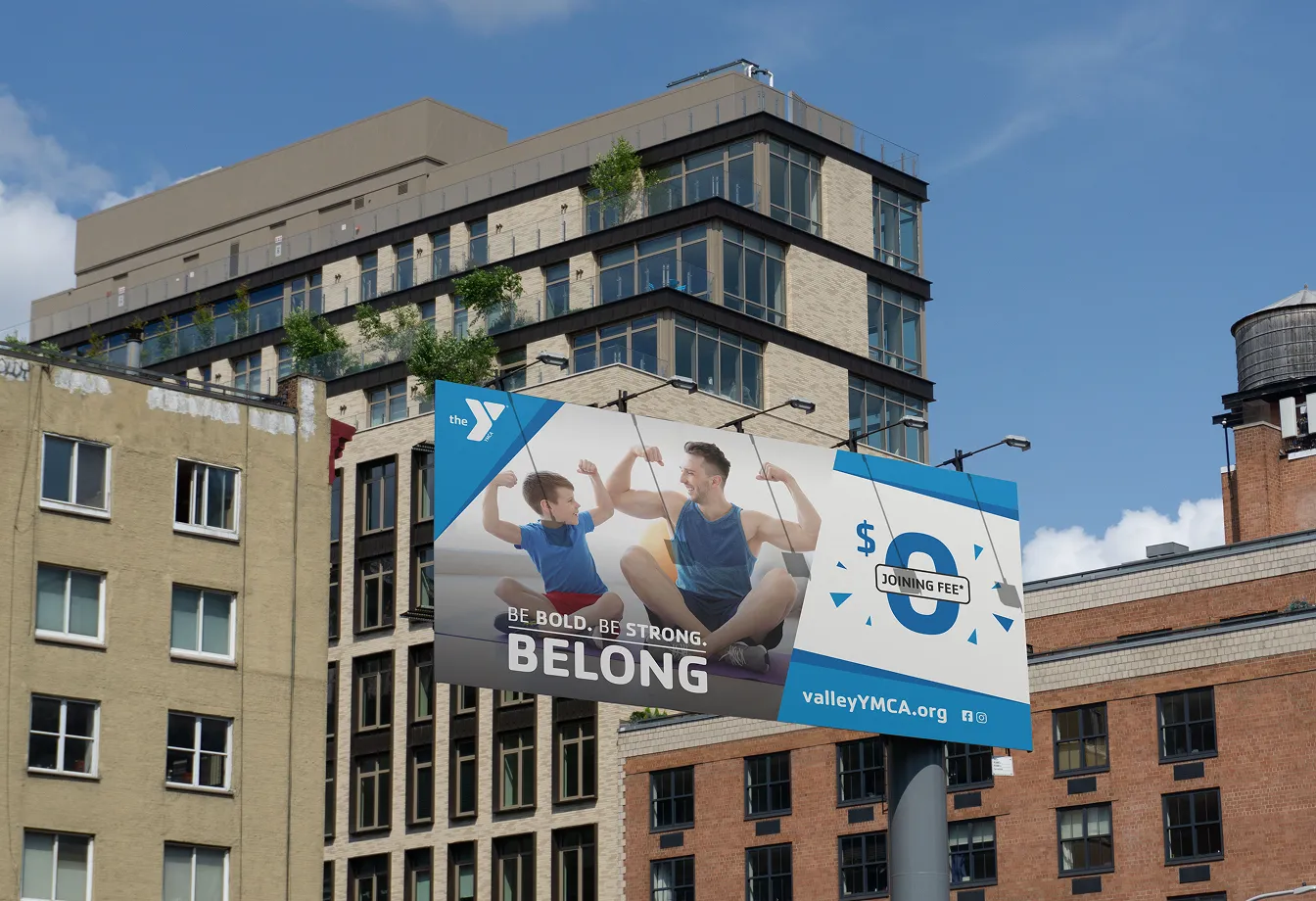 A YMCA "Belong" billboard mounted on a city apartment building.
