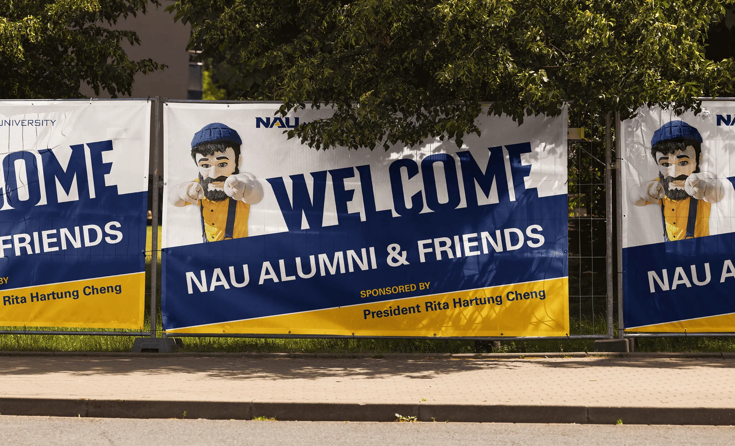 Outdoor banners welcoming NAU alumni and friends, with the Lumberjack mascot.