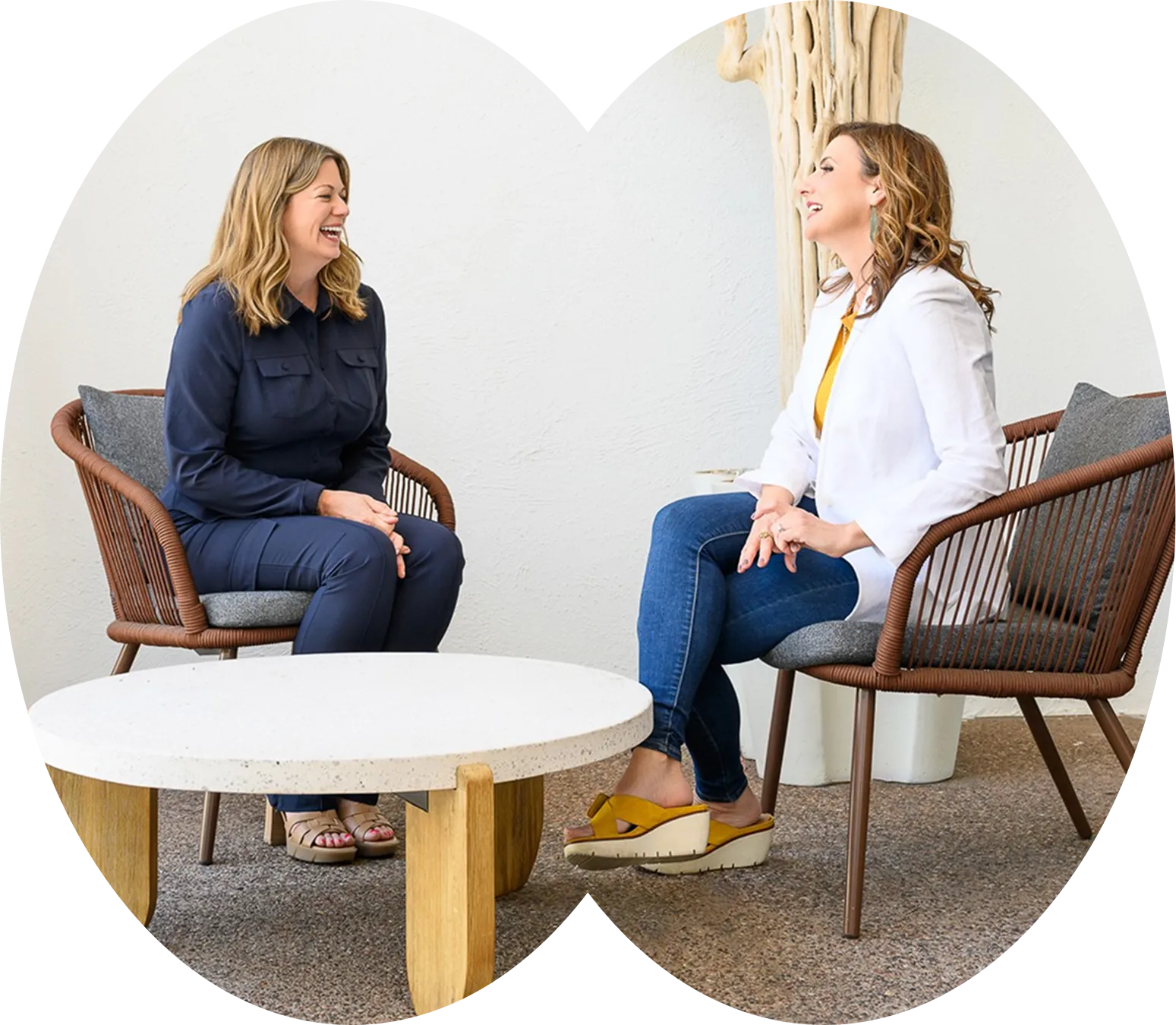 Two women in conversation in armchairs, shown in arched crops.