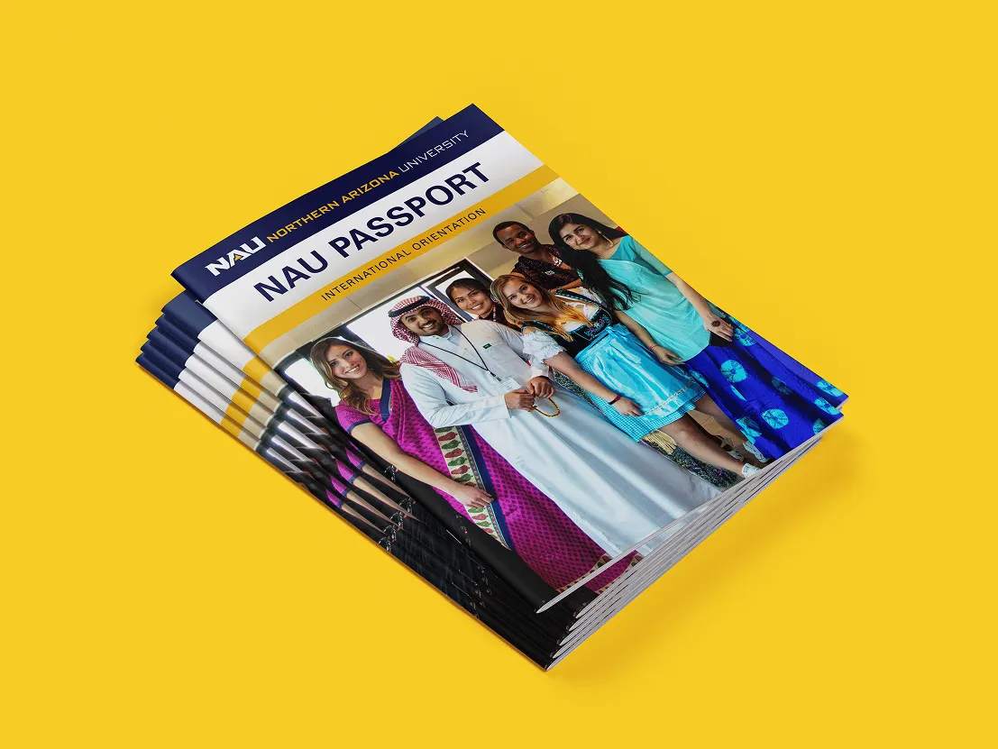 A stack of NAU Passport orientation booklets showing students in traditional attire.