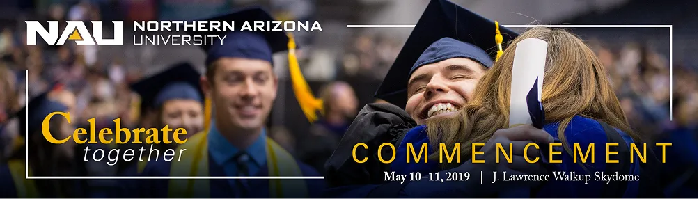 Graduates in caps and gowns hugging in celebration at commencement.