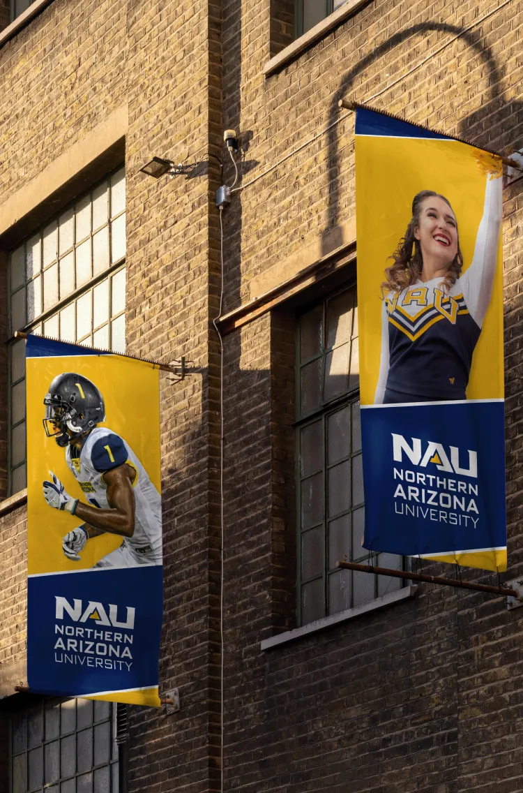 NAU banners on a brick wall showing a football player and a smiling cheerleader.