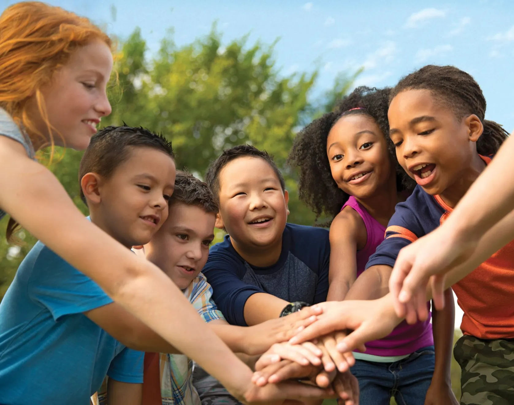A group of children stacking their hands together in a team huddle.