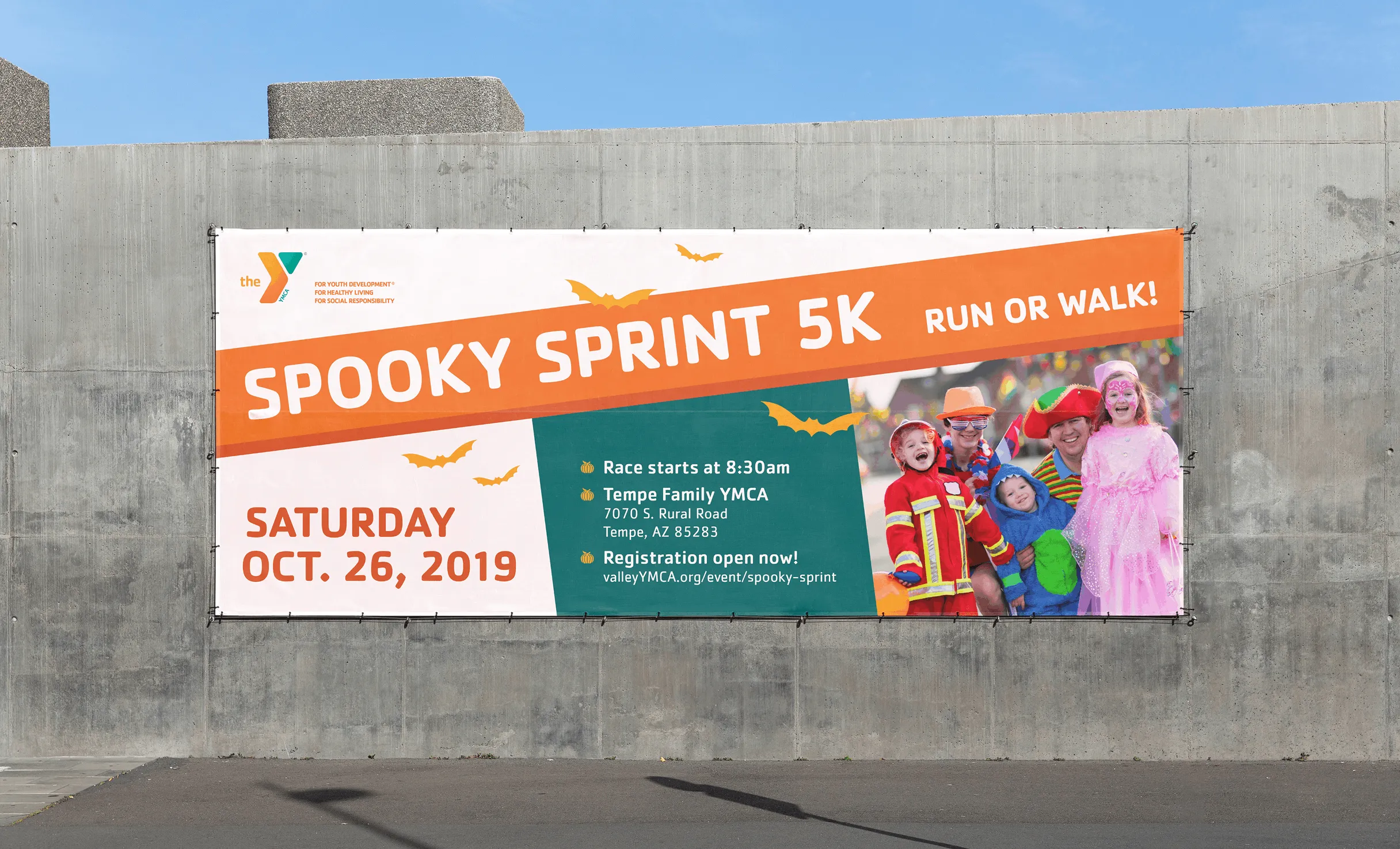 A YMCA "Spooky Sprint 5K" banner on a concrete wall advertising a run or walk in October.