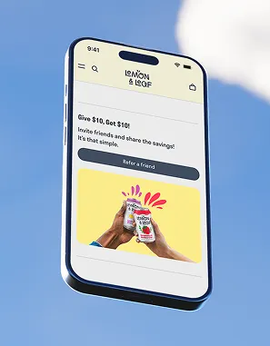 A phone against a blue sky showing a Lemon & Leaf referral screen with two hands toasting.