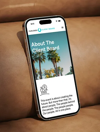A phone propped on a leather sofa showing the Paradox Client Board "About The Client Board" page, headed by a photograph of palm trees.