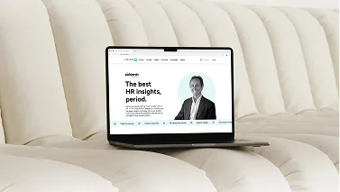 A laptop resting on a cream sofa, displaying a Paradox page headlined "The best HR insights, period." beside a portrait photograph.