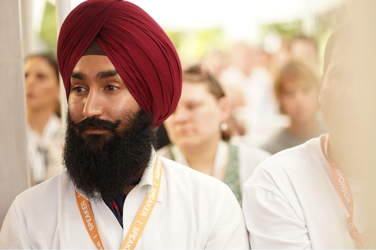 A man in a red turban among attendees at a summit gathering.