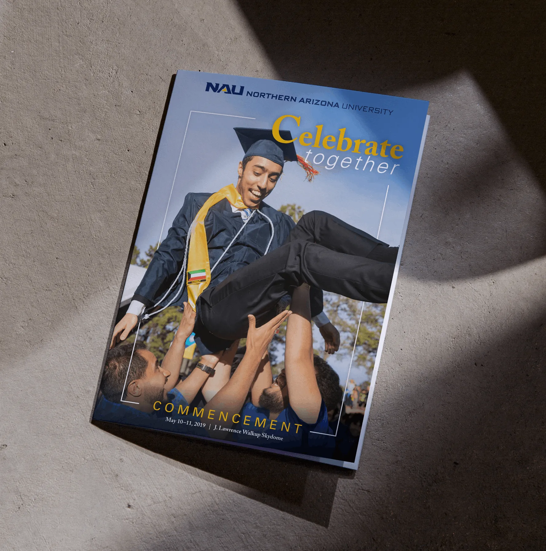 Northern Arizona University commencement booklet with graduate being lifted joyfully by friends.