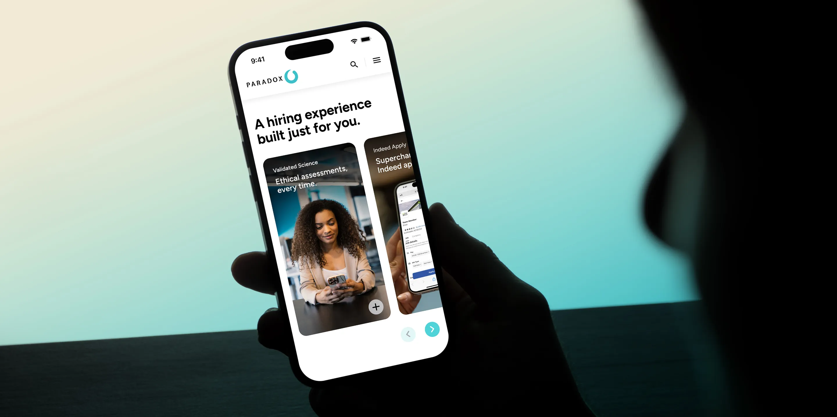 A hand holding a phone showing the Paradox site headlined "A hiring experience built just for you."