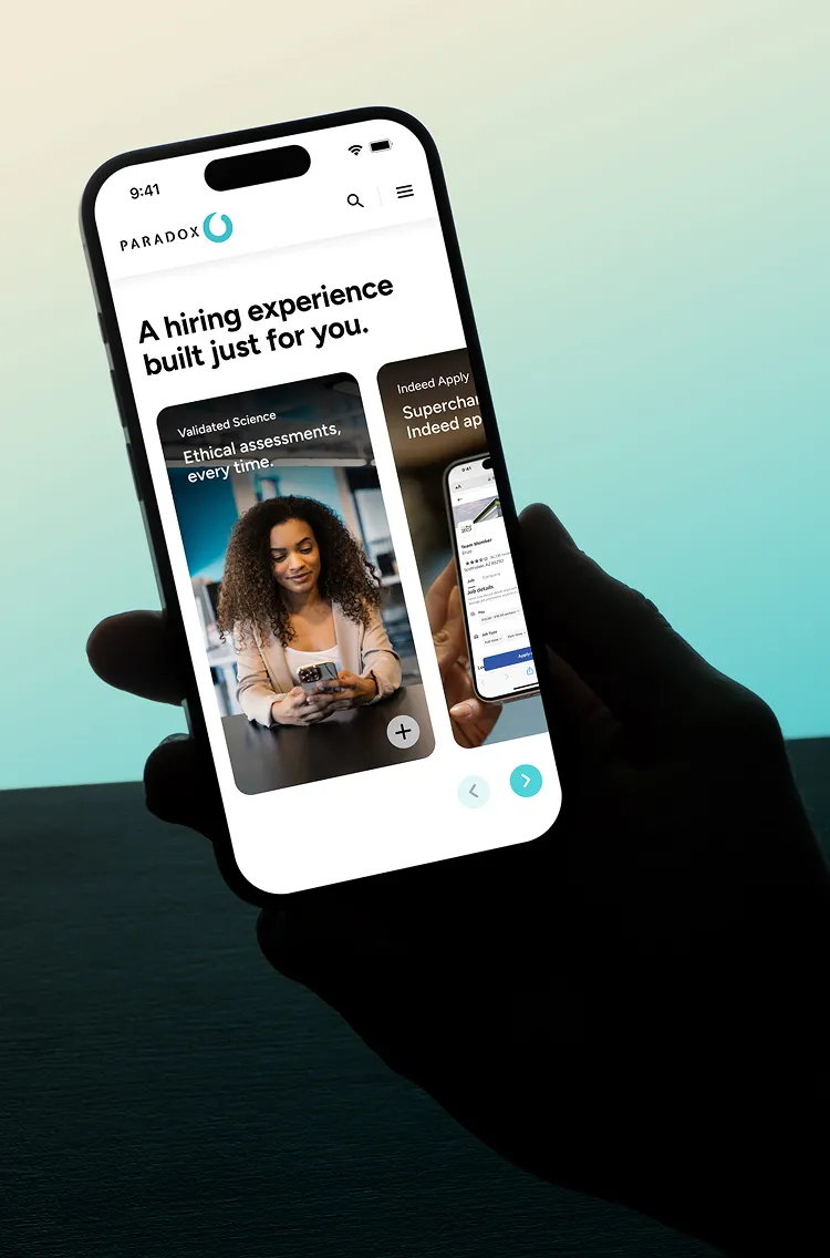 A hand holding a phone showing the Paradox site headlined "A hiring experience built just for you."