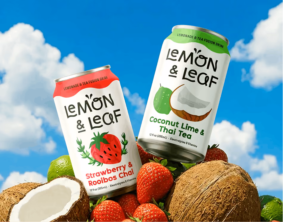 Two Lemon & Leaf cans, Strawberry & Rooibos Chai and Coconut Lime & Thai Tea, standing on a heap of fresh strawberries, halved coconuts and limes against a bright blue sky.