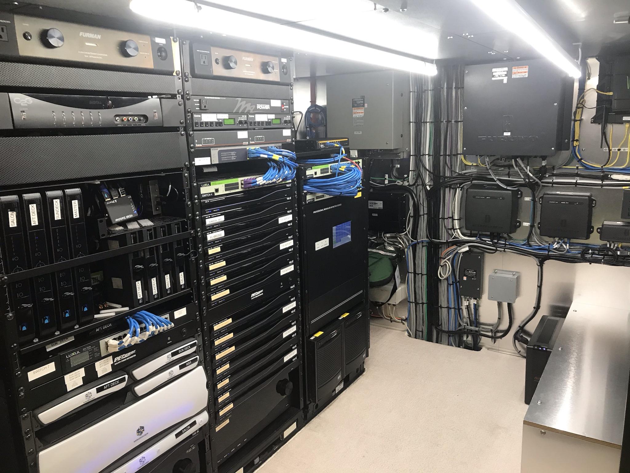 Network and server rack with cables and equipment in a well-organized data or control room.