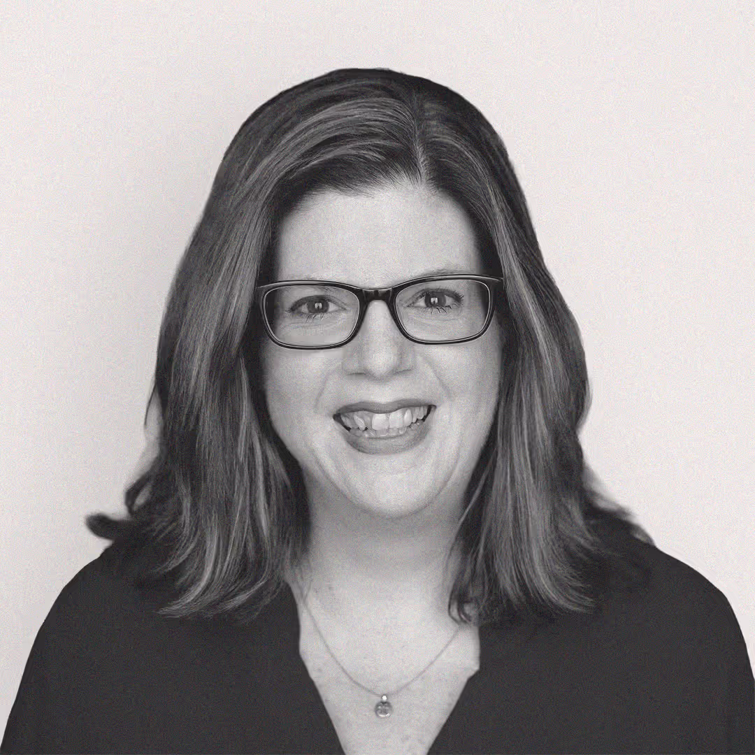 Headshot of Kelly Carpenter, VP of Service Delivery at axa·nexa, smiling with shoulder-length hair, glasses, and a necklace, wearing a dark top.