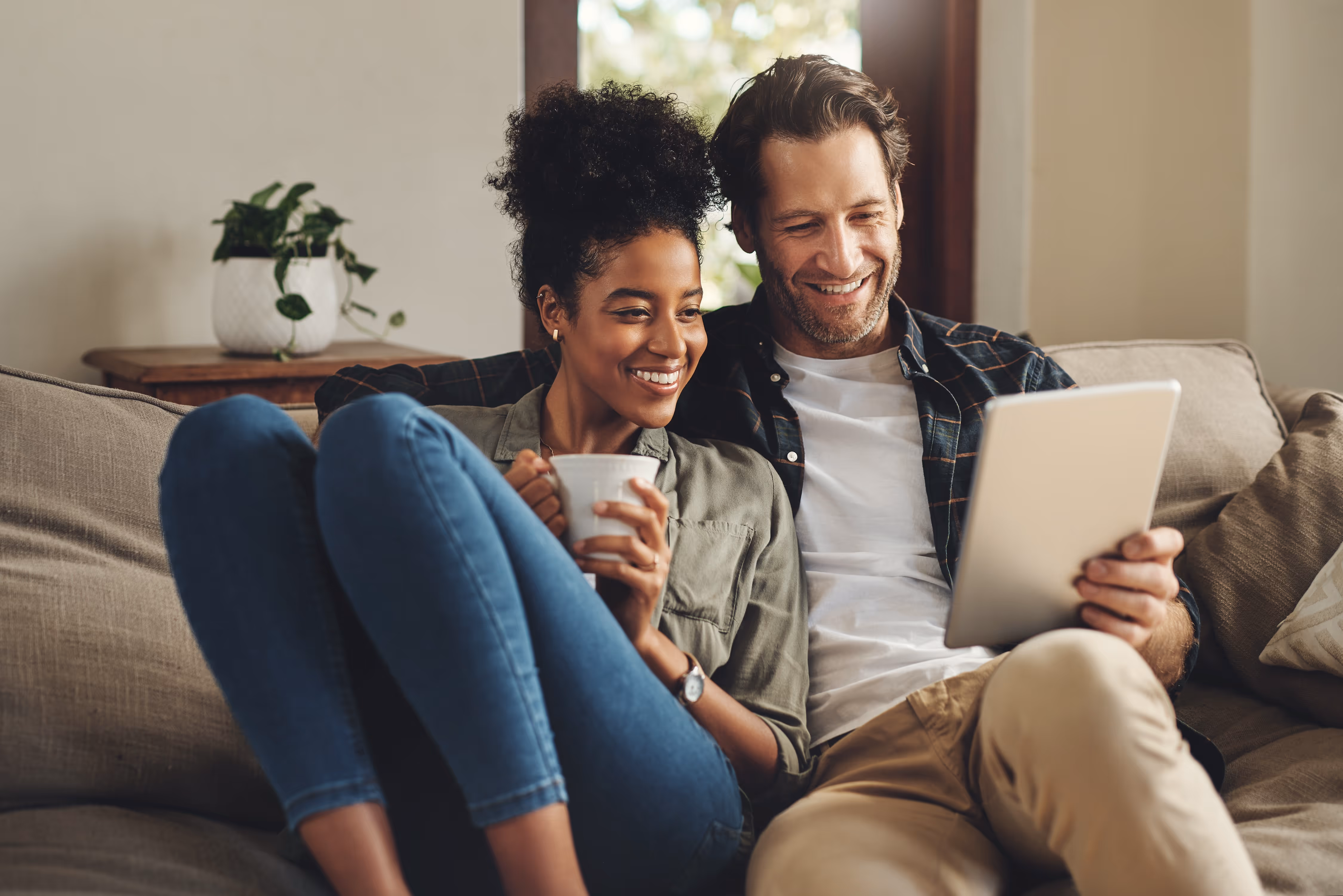 Man and woman sitting on the couch looking at the ipad stock image