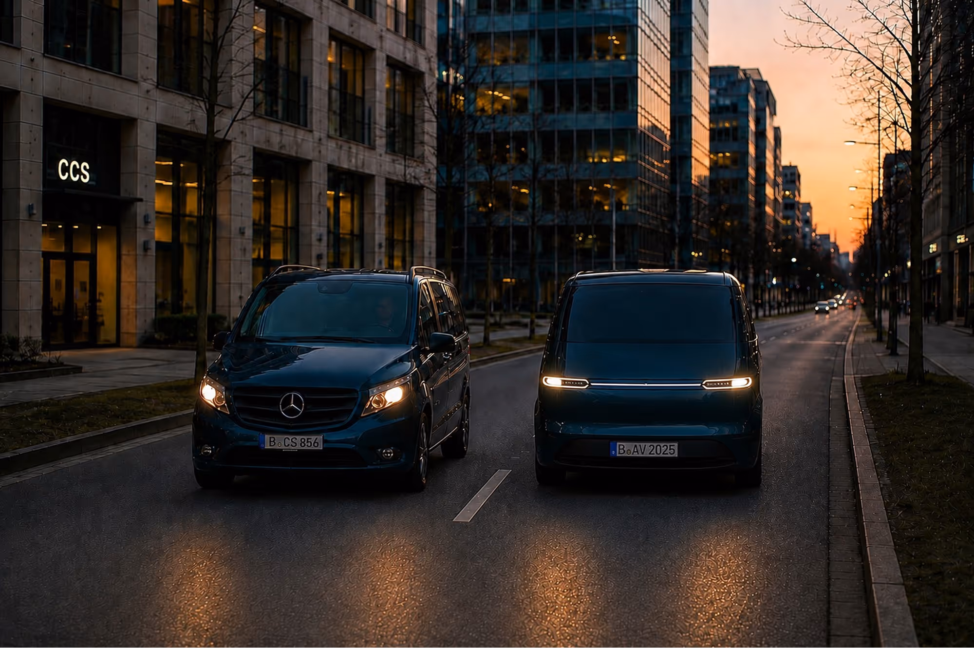 Zwei dunkle Vans fahren bei Dämmerung auf einer Straße zwischen modernen Gebäuden in der Stadt.