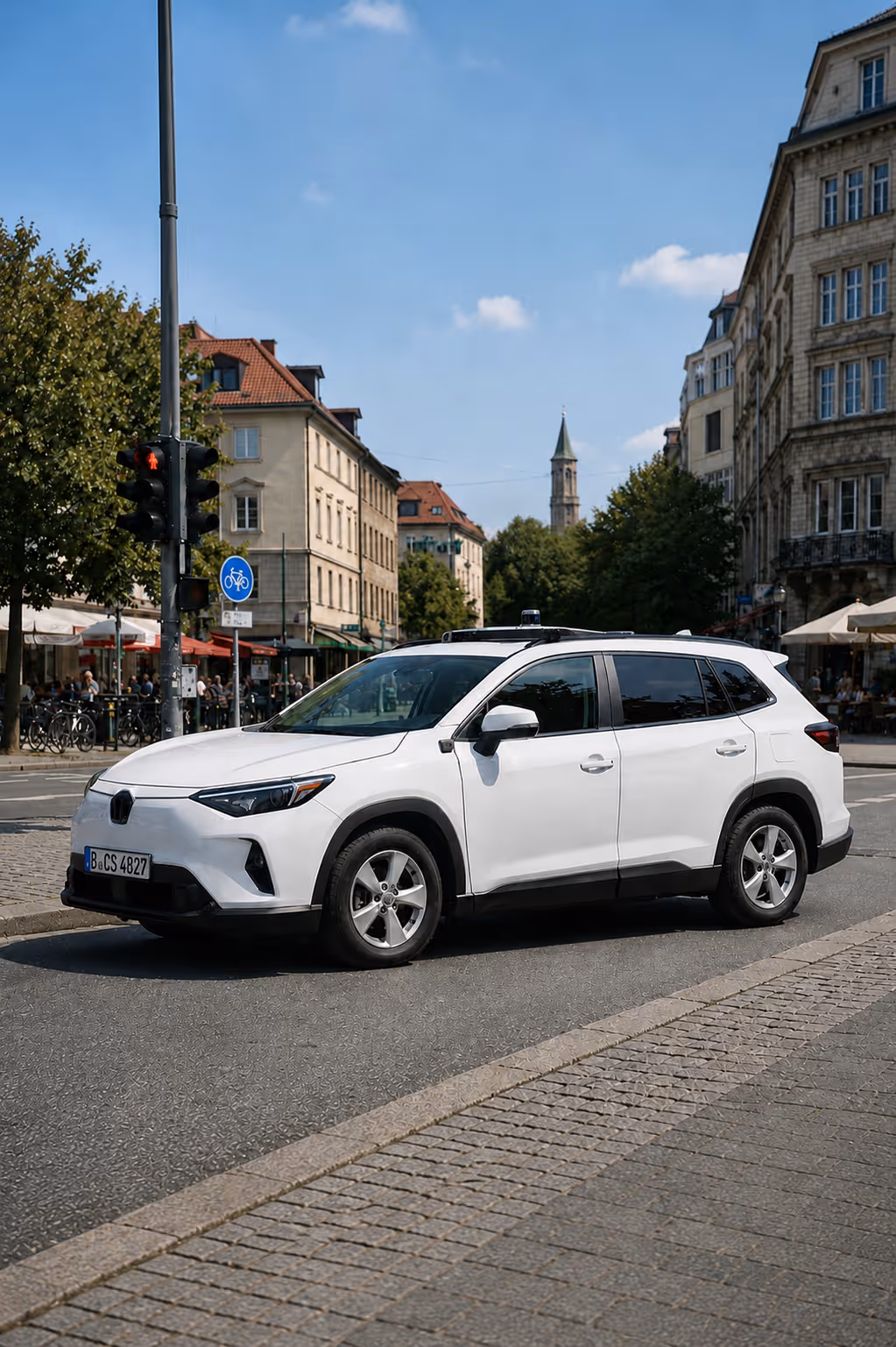 Weißes SUV steht an einer Ampel in einer Stadtstraße mit historischer Architektur.