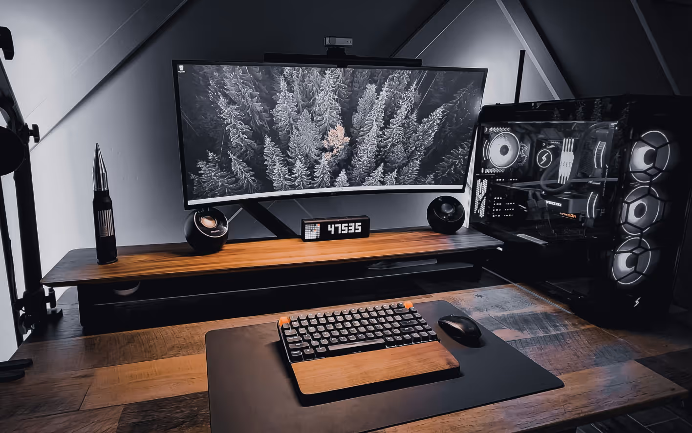 Modern PC setup with curved widescreen monitor, mechanical keyboard, mouse, and illuminated PC case.