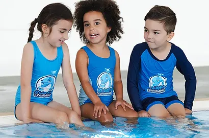 Children in BlueFit Swimming swimwear sitting beside the pool
