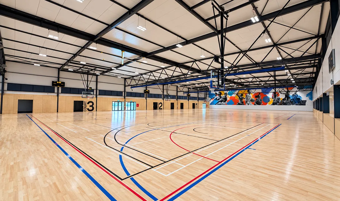 Indoor sports court with people playing basketball