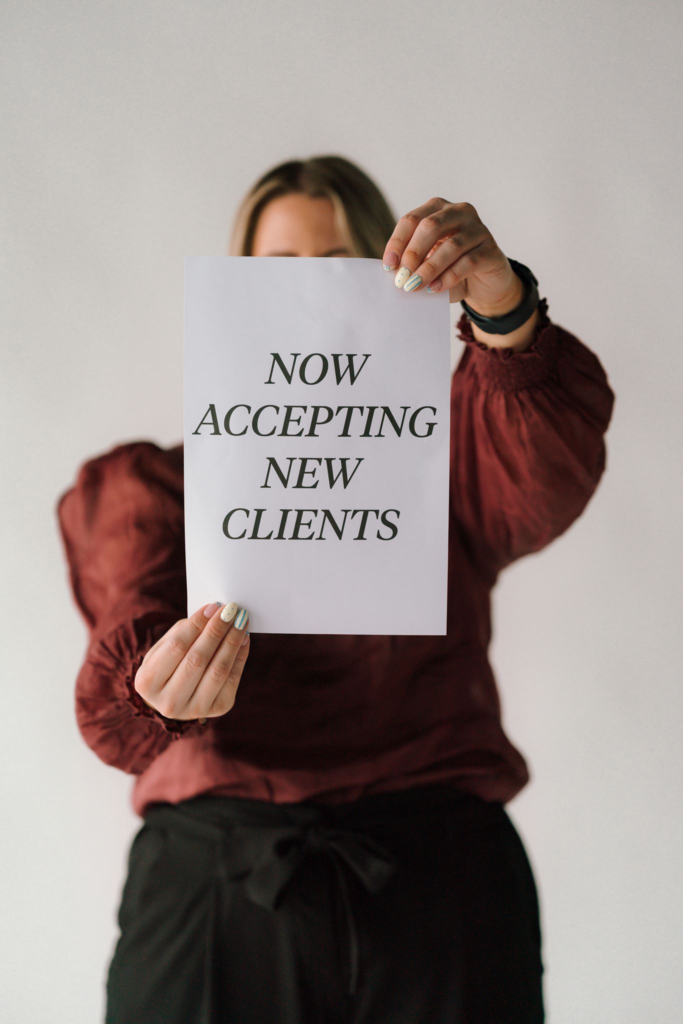 Tam holding a paper with "now accepting new clients" to the camera