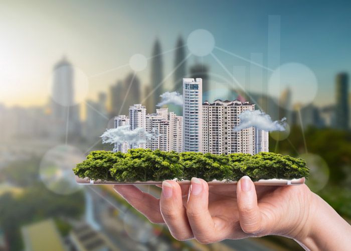 Hand hält ein Modell einer modernen Stadt mit Hochhäusern und grünen Bäumen, digitales Netzwerk im Hintergrund.