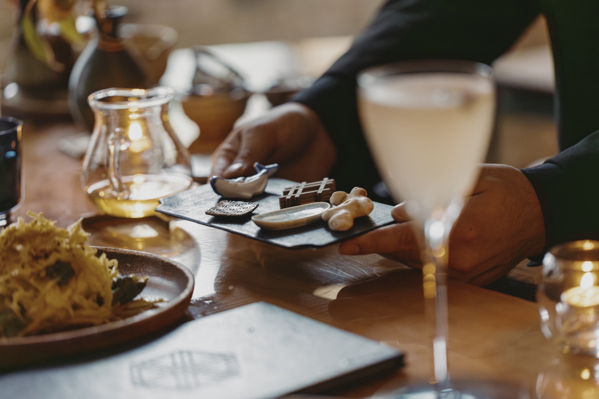 A garnish tray presented beside a clarified cocktail at the counter