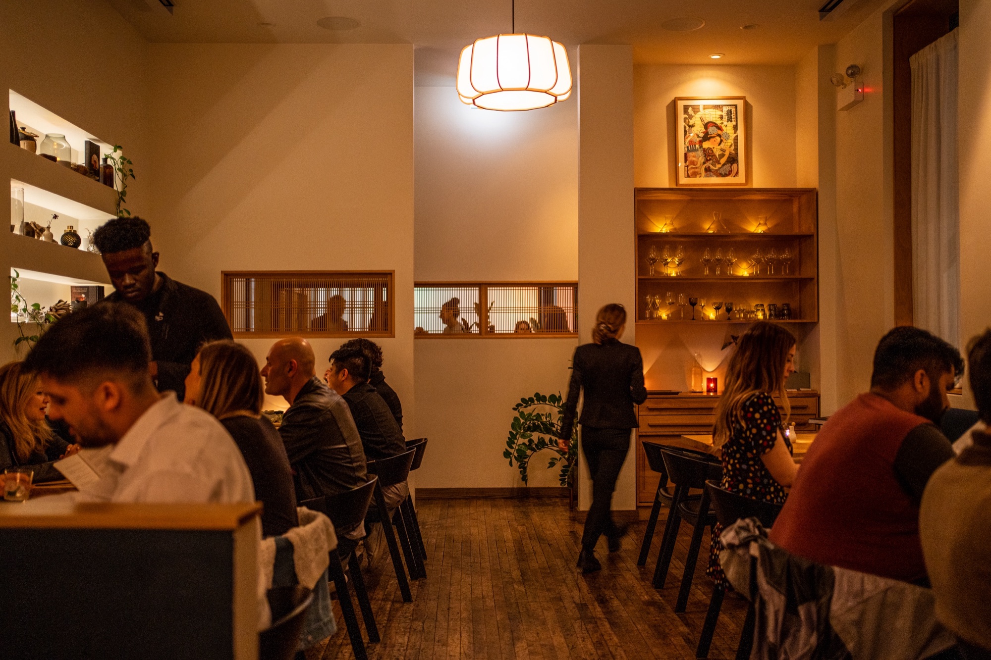 The Kumiko dining room in the evening, guests at tables beneath a paper pendant lamp