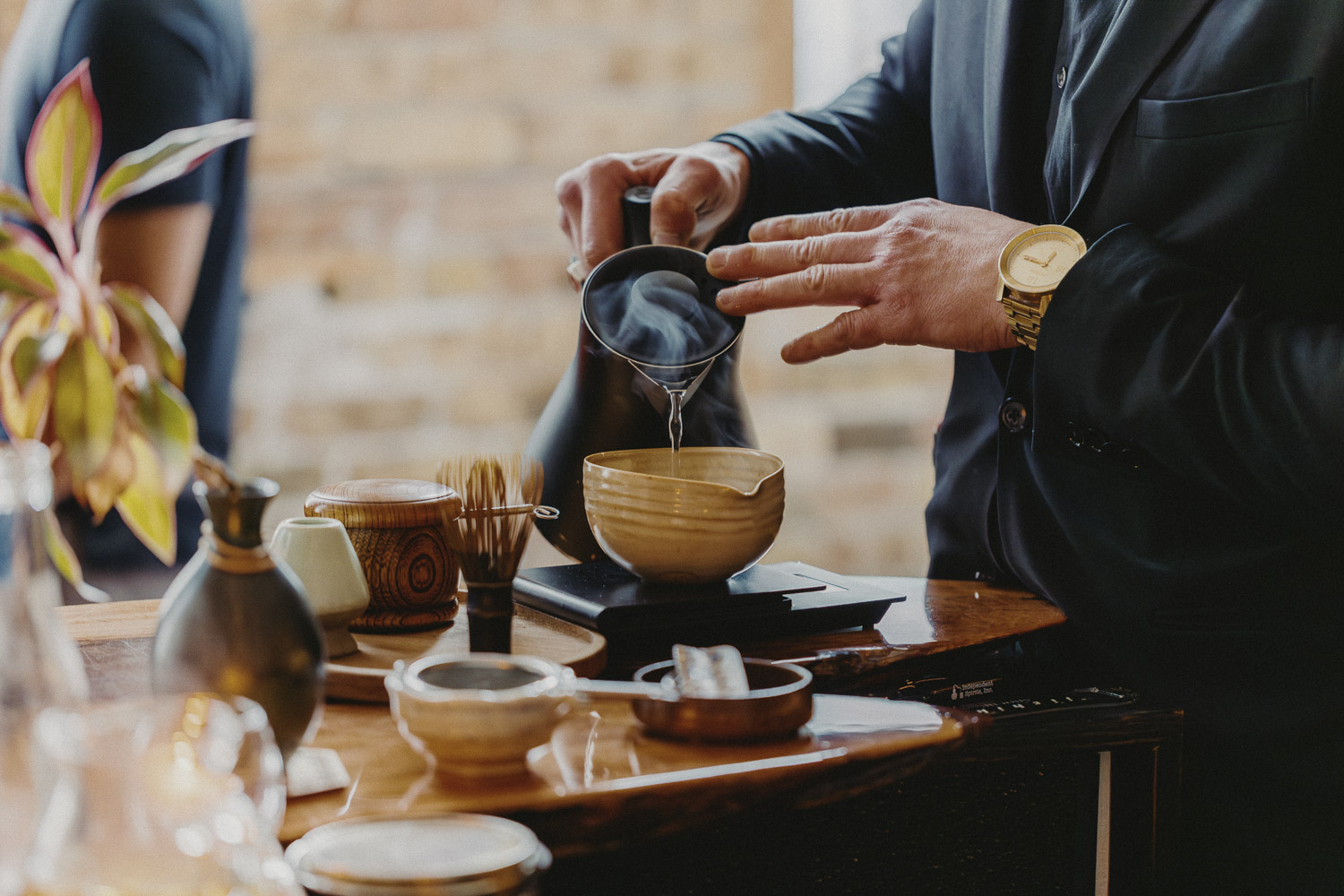 A pour-over coffee being brewed beside a matcha bowl and whisk at Café Kumiko
