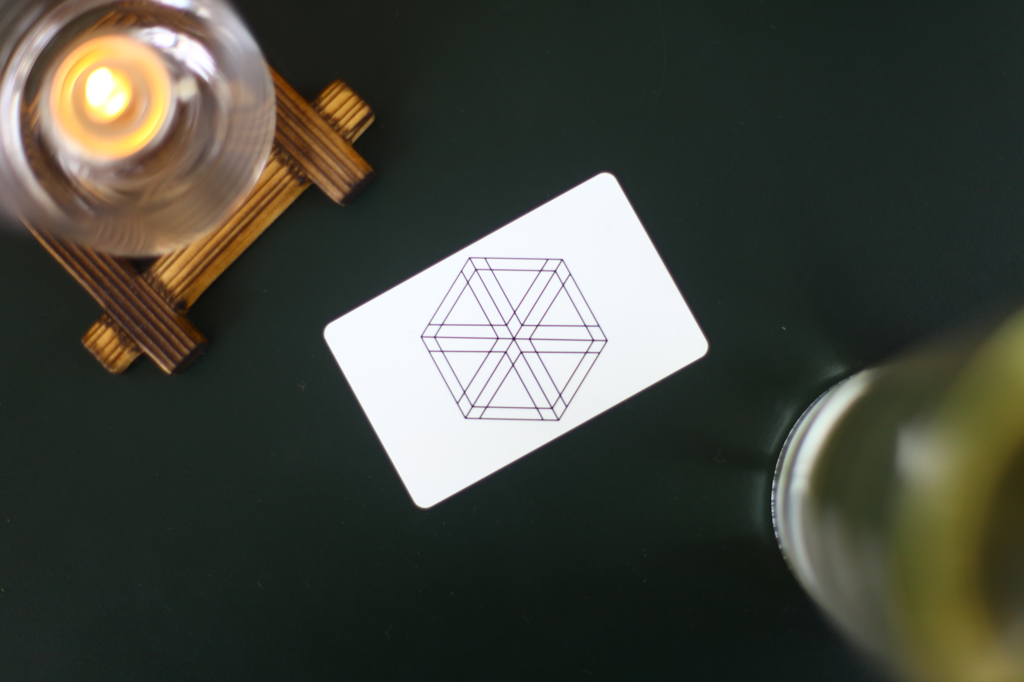 A white Kumiko gift card with the hexagonal kumiko-pattern mark, beside a lit candle