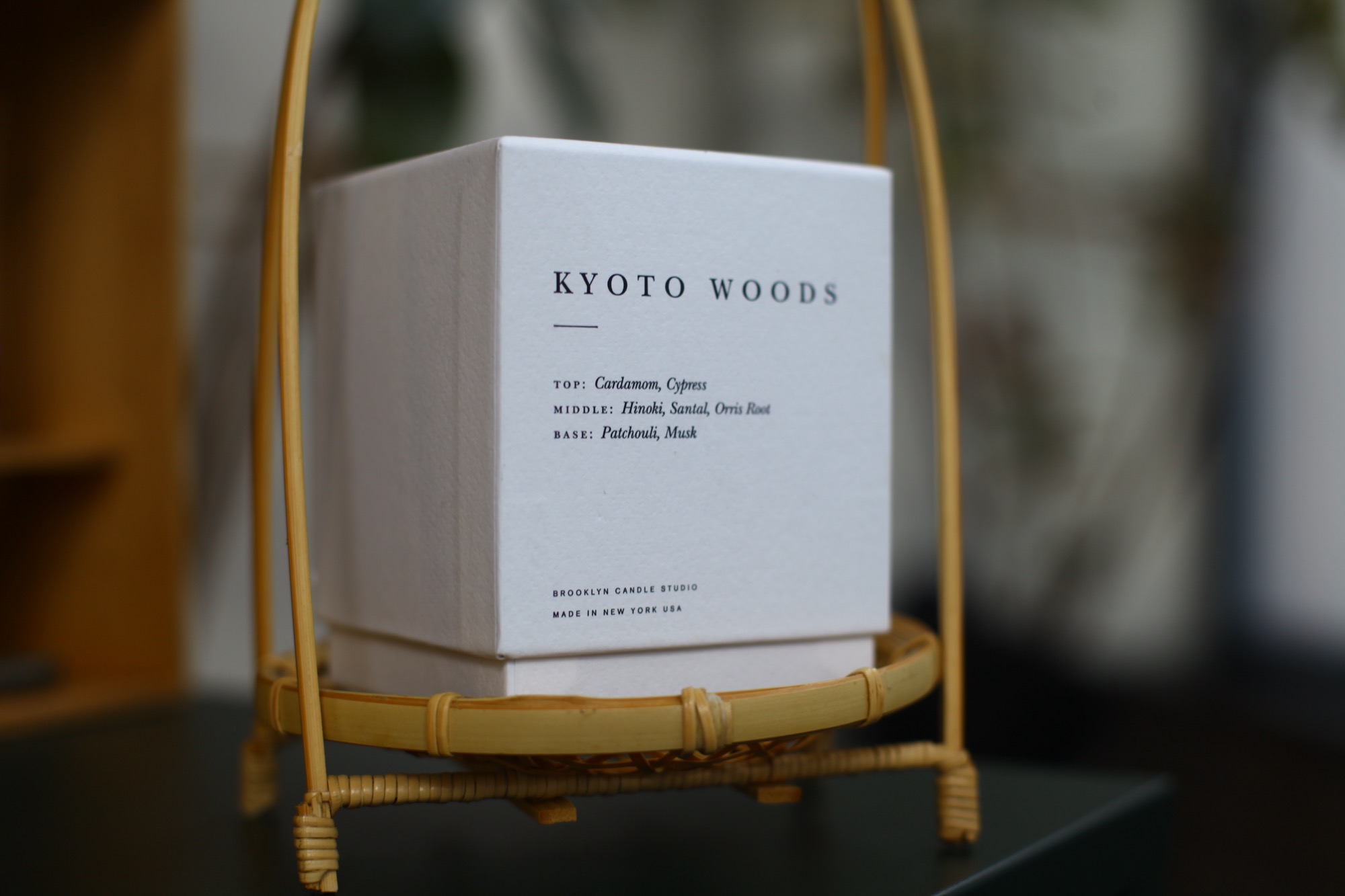 A white Brooklyn Candle Studio "Kyoto Woods" box resting on a bamboo stand