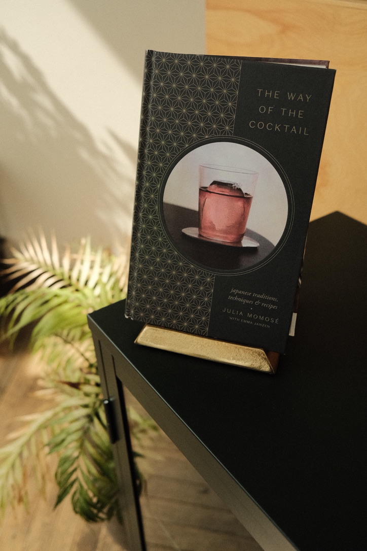 The Way of the Cocktail by Julia Momosé standing upright on a brass book rest