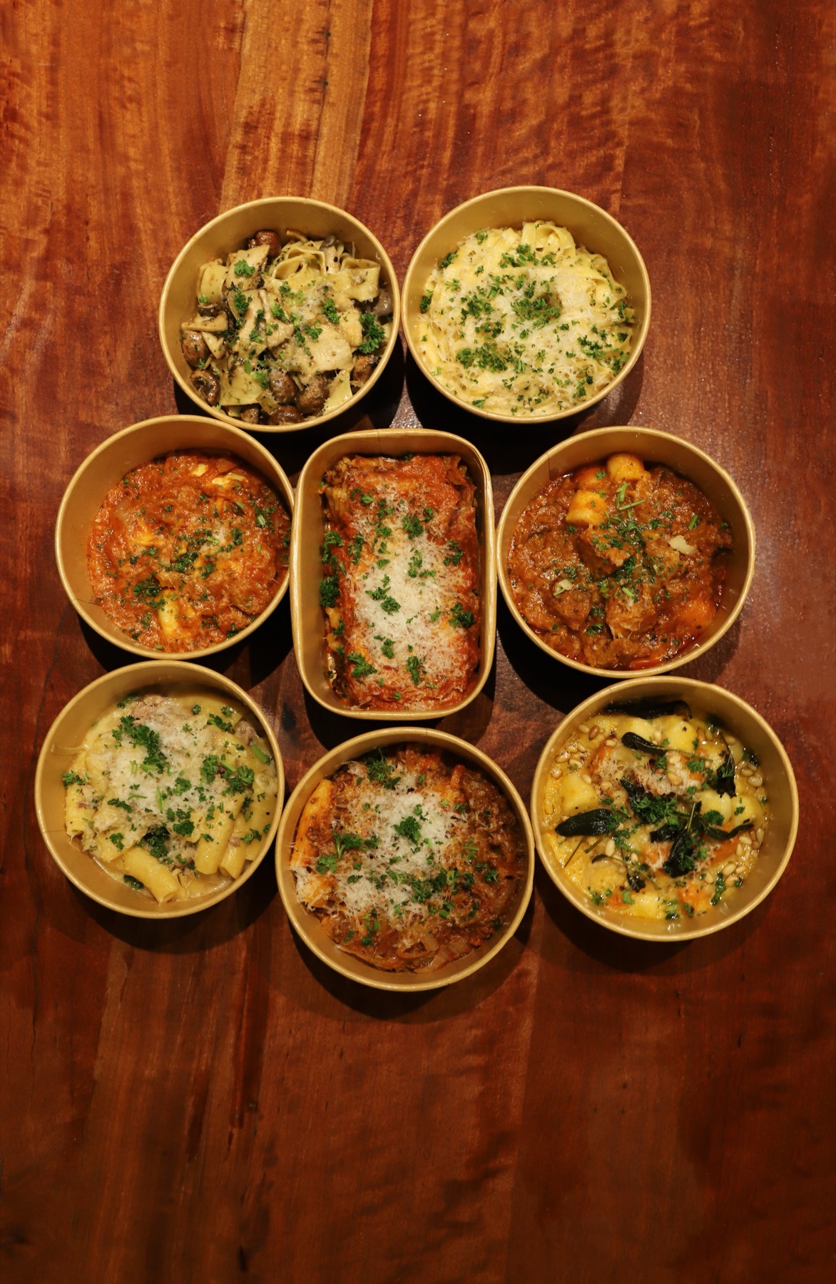 Eight Obertor Pasta Bar dishes arranged in a circle on a dark wooden table