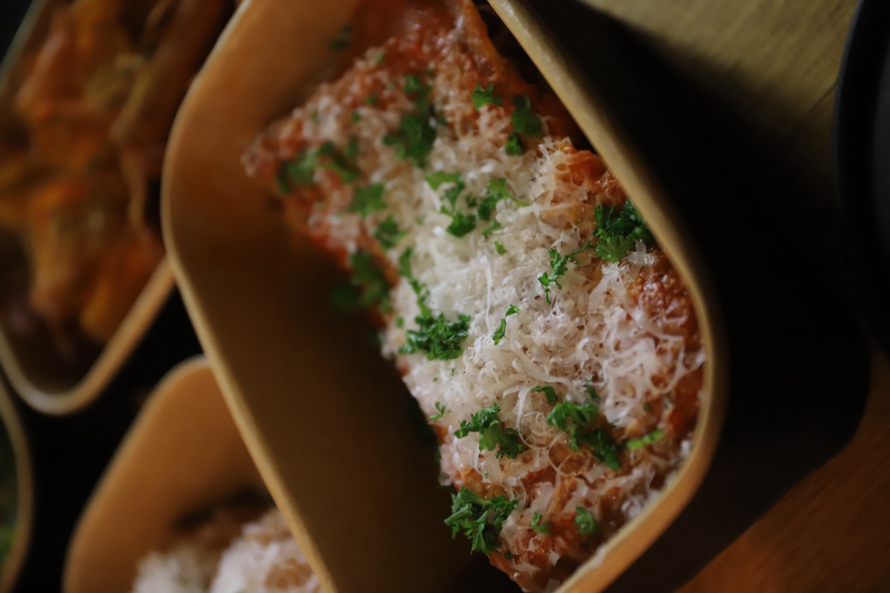 Close up of Nonna's beef lasagne finished with parmesan in its takeaway box