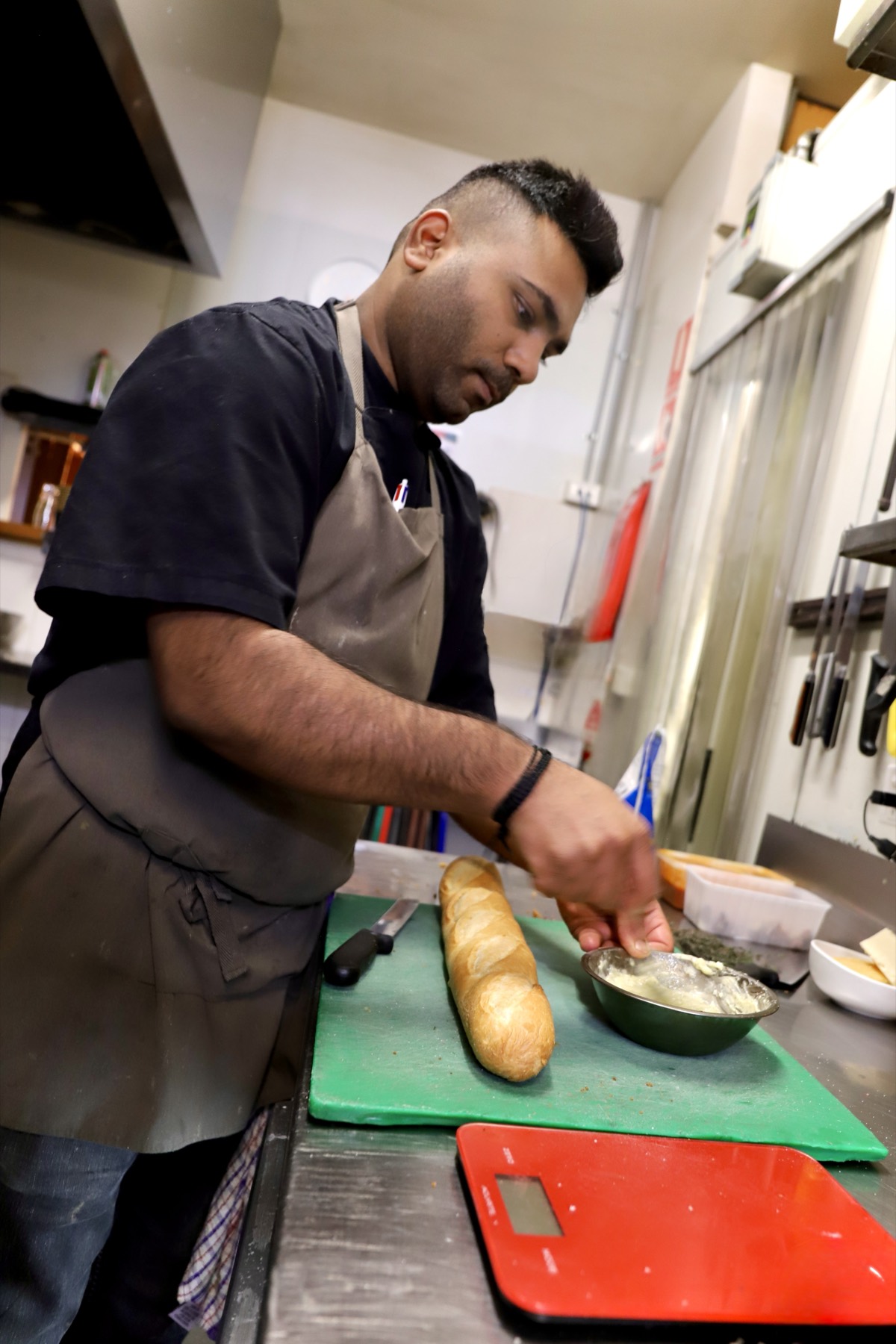 Obertor chef spreading garlic butter on a house baked baguette