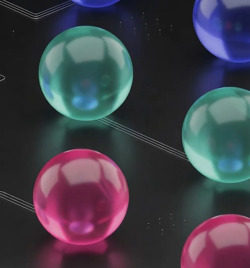 Shiny translucent spheres in blue, green, and pink colors connected by thin lines on a dark surface.
