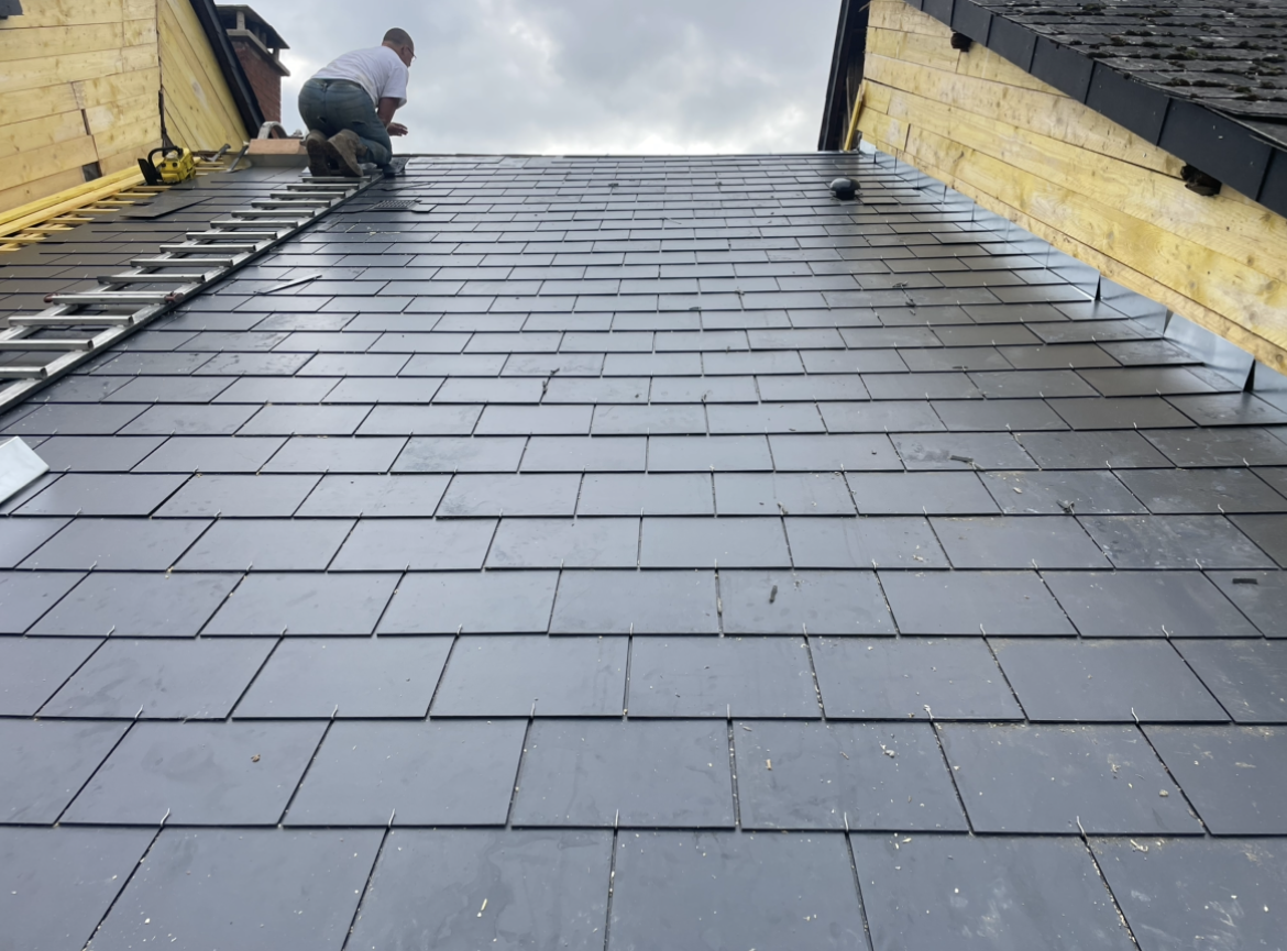 Toit ardoise neuf, alignement parfait, couleur gris uniforme, aucune détérioration, ciel nuageux.