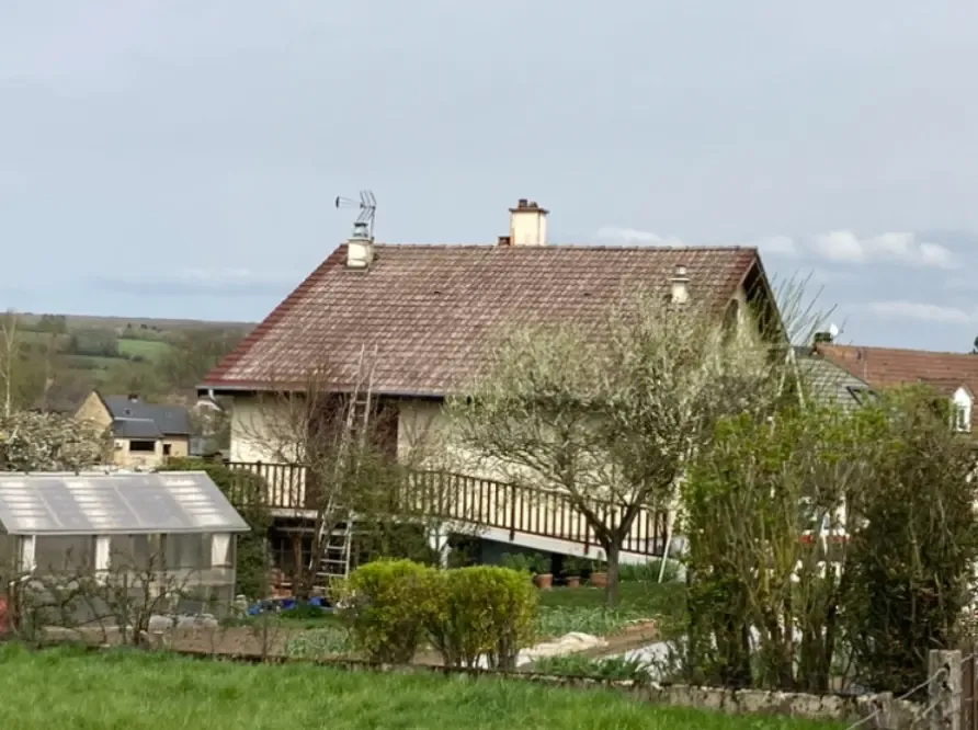 Toiture tuiles rouges encrassées, mousse verte, traces noires sous ciel couvert, Bazeilles.