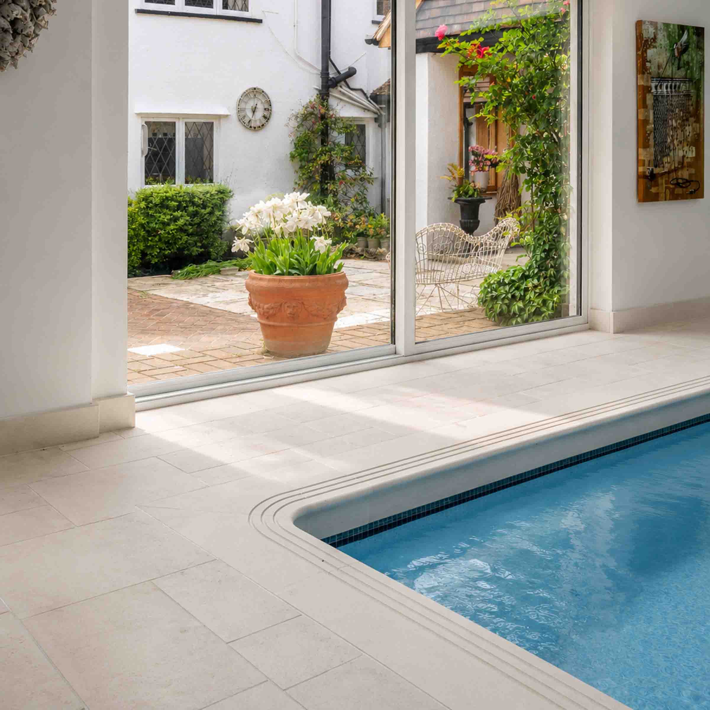 Bespoke natural stone swimming pool surround and flooring designed and installed by Coulon Stone