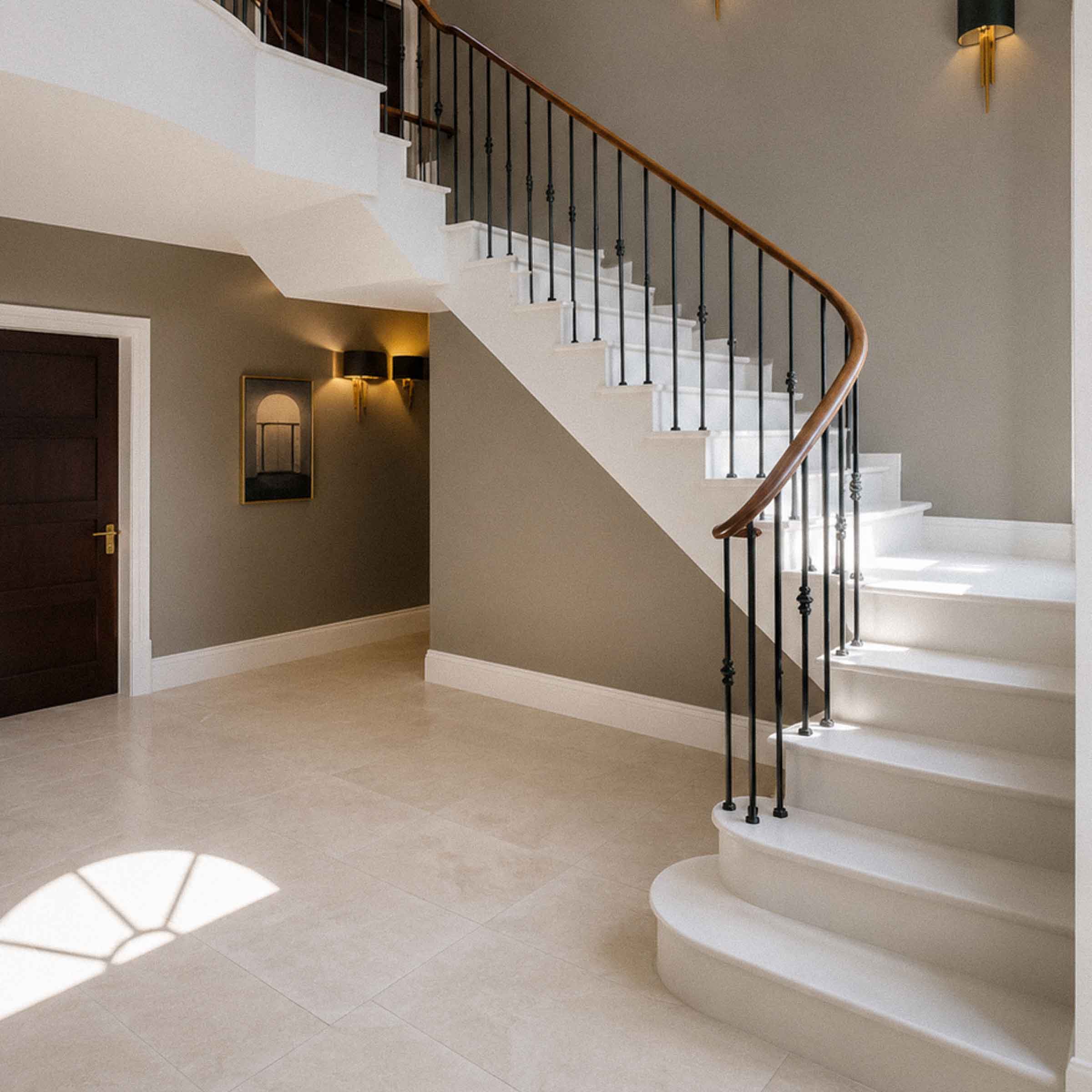 Bespoke natural stone staircase with sweeping curved design and handcrafted iron balustrade