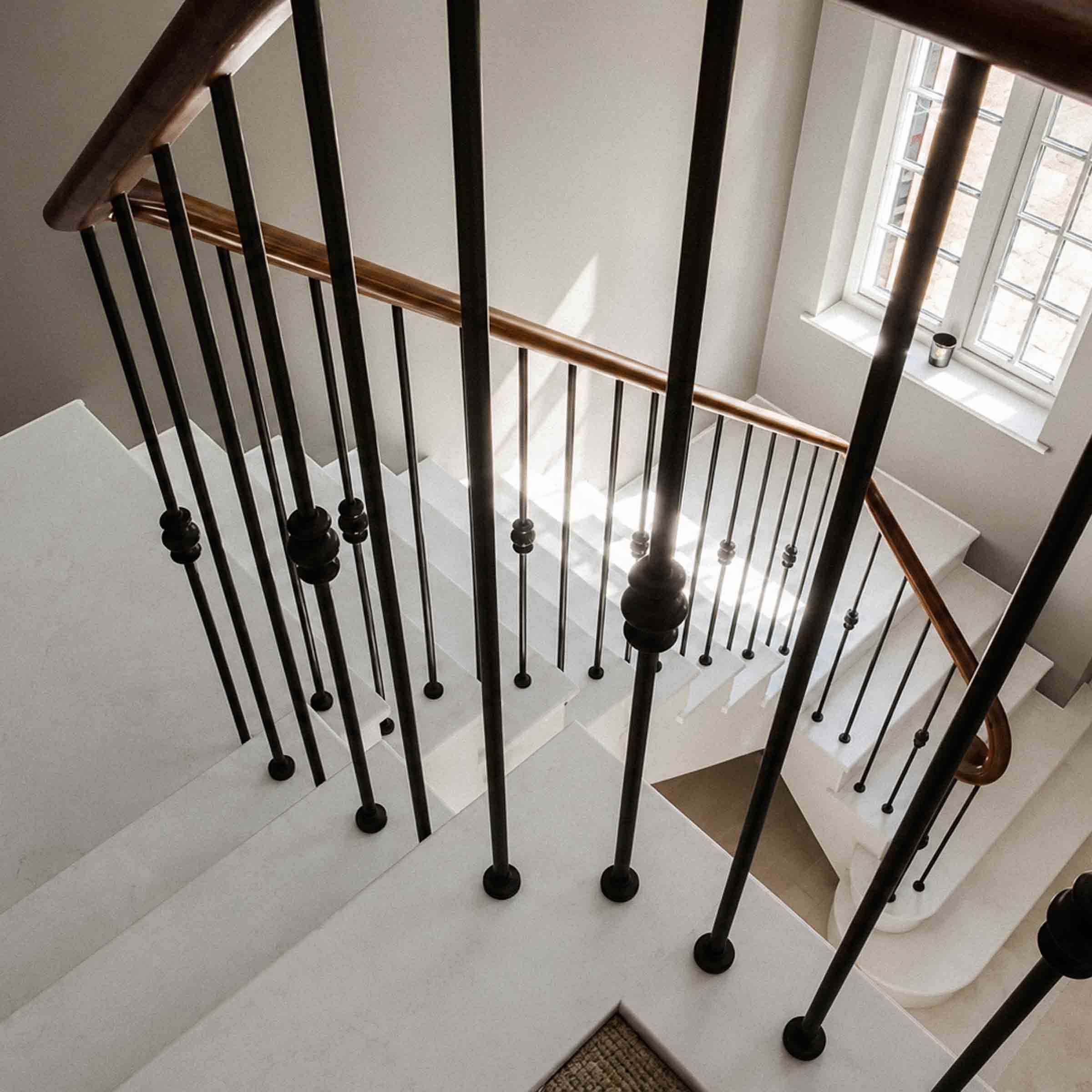 Bespoke natural stone staircase with sweeping curved design and handcrafted iron balustrade