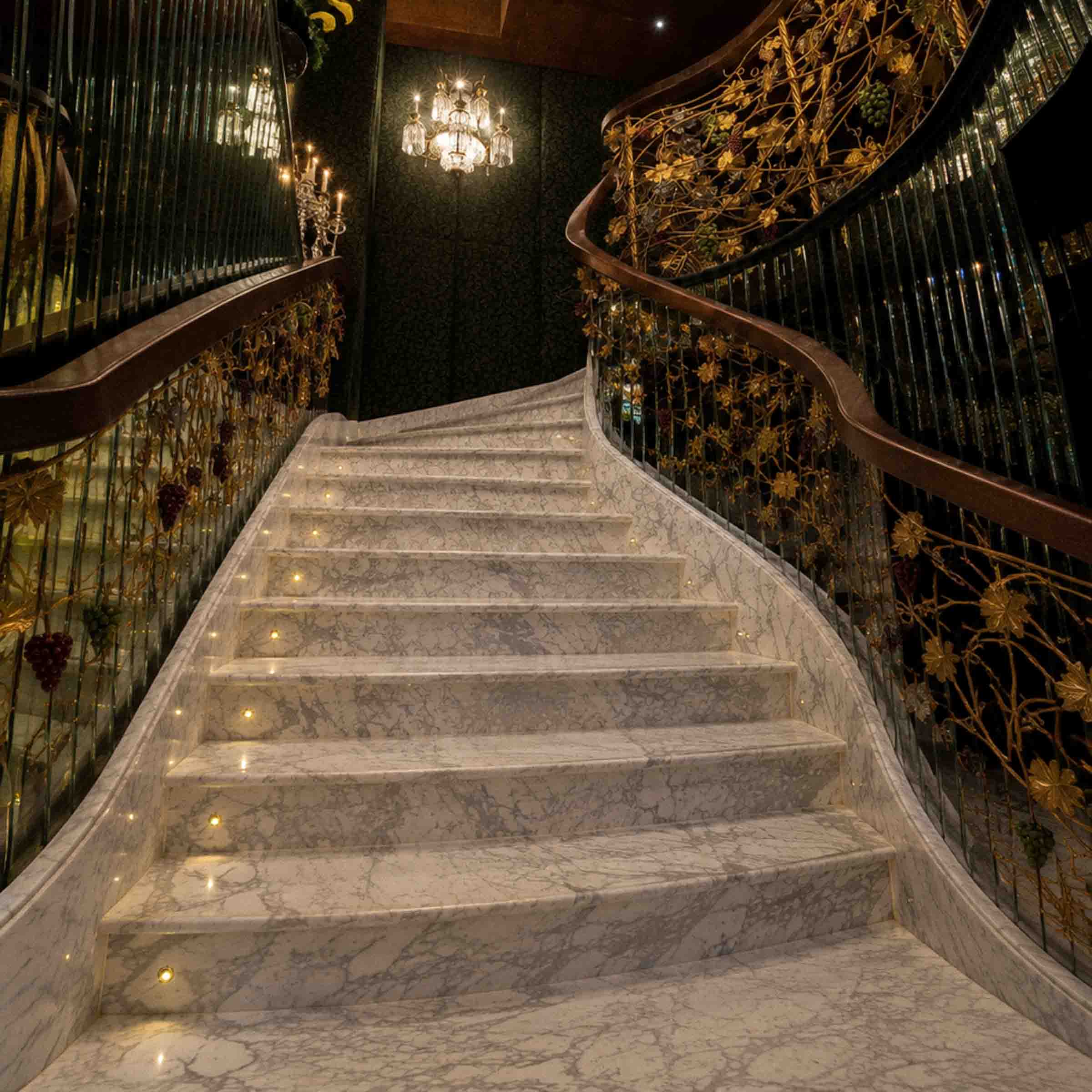 Bespoke natural stone staircase with sweeping curved design and handcrafted iron balustrade