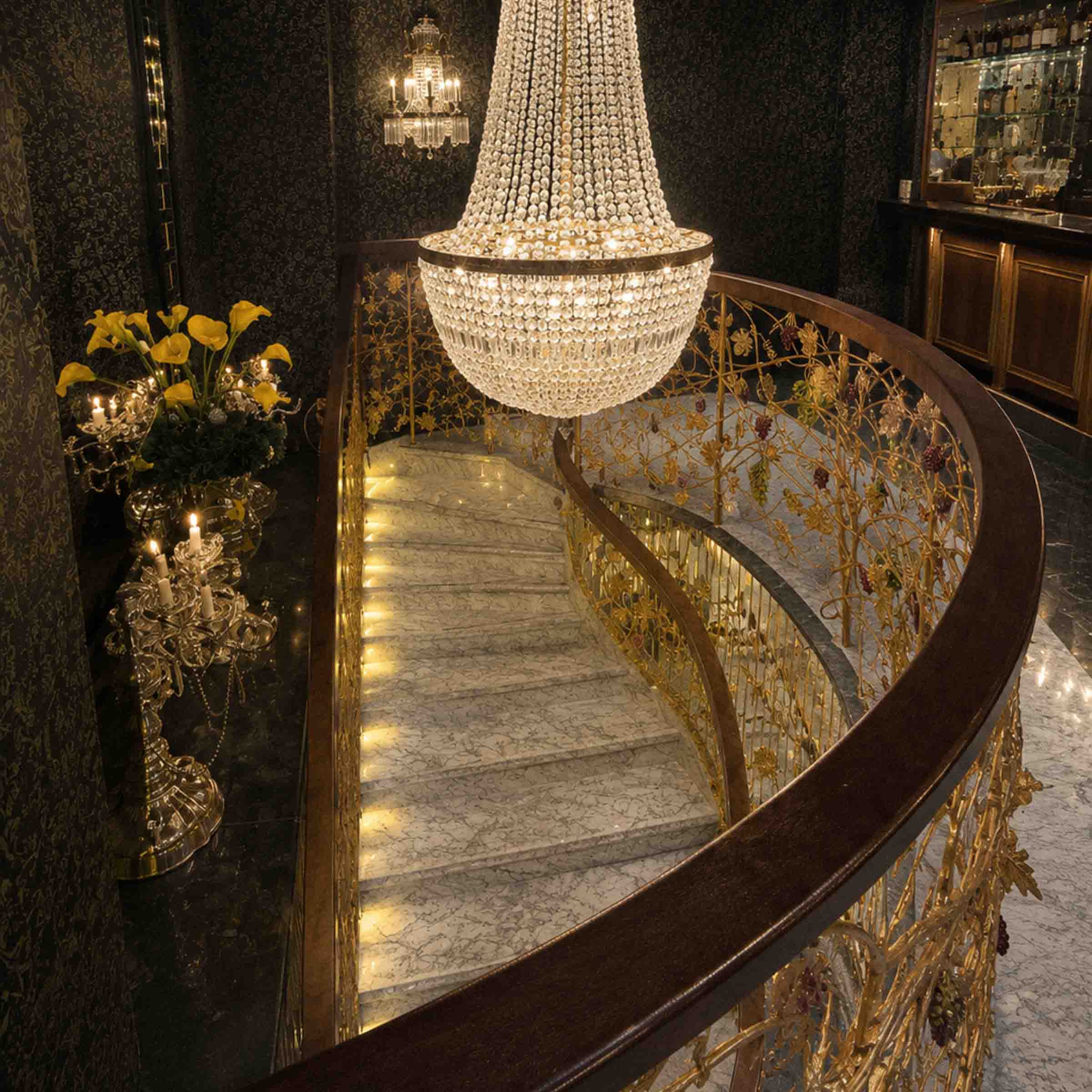 Bespoke marble staircase with sweeping curved design and handcrafted iron balustrade