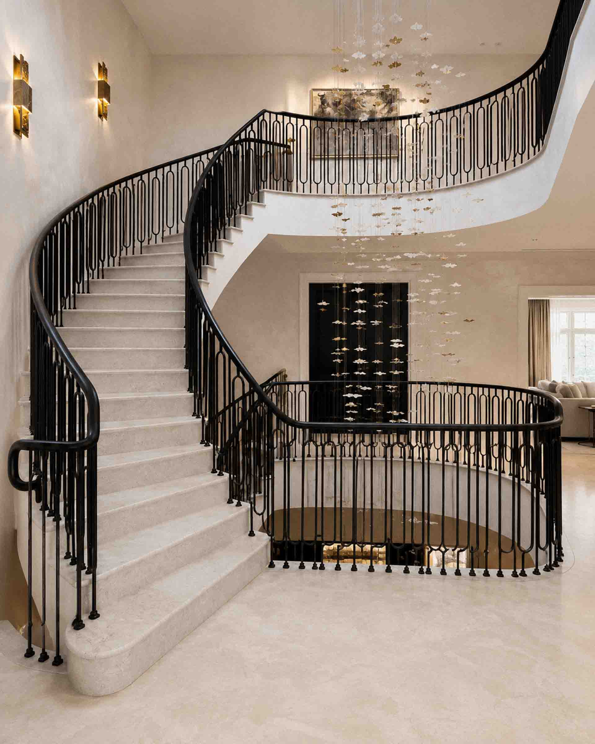 Bespoke marble staircase with sweeping curved design and handcrafted iron balustrade