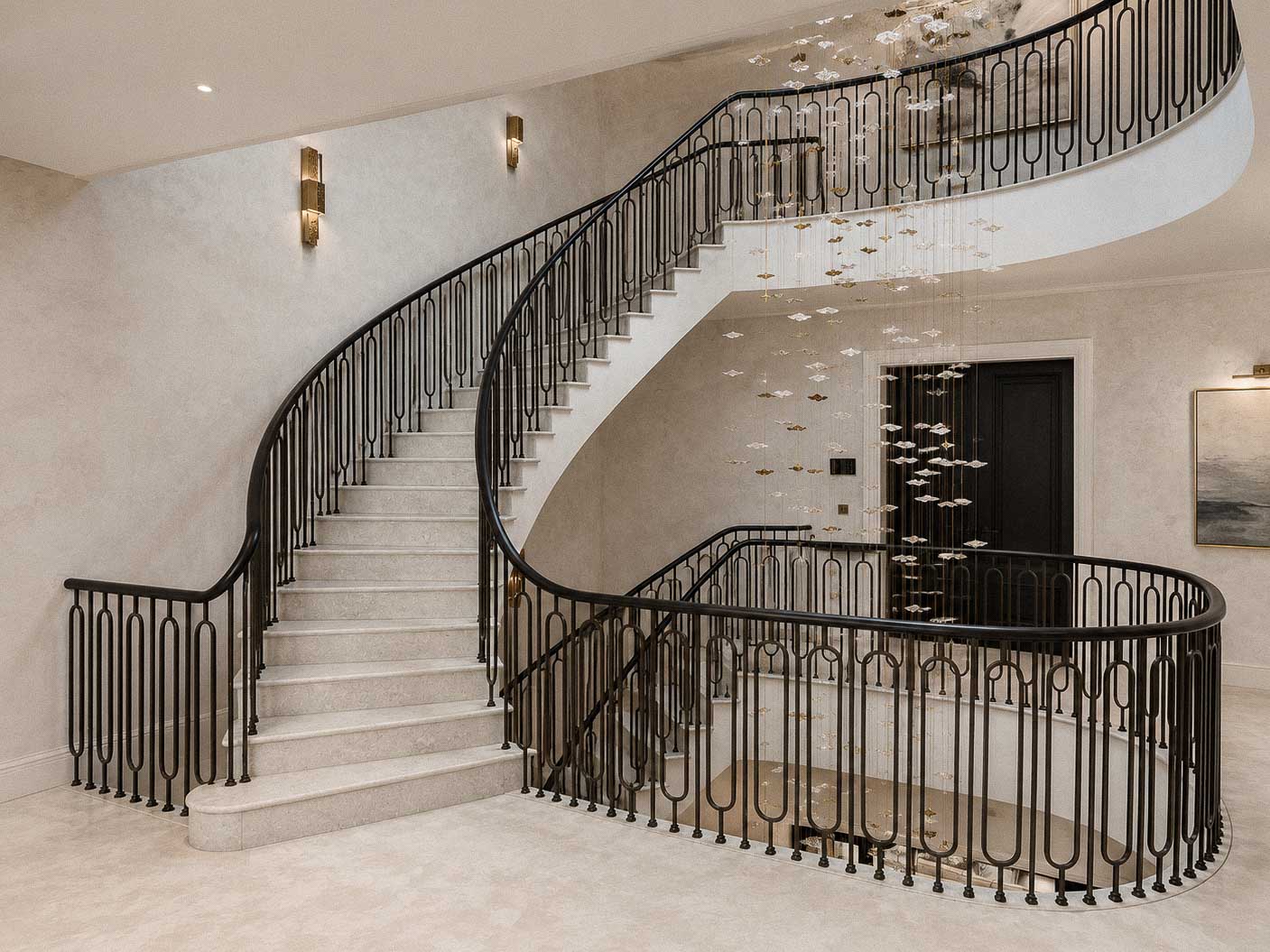 Bespoke natural stone staircase with sweeping curved design and handcrafted iron balustrade