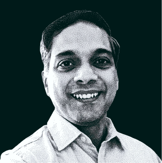 Smiling man wearing a collared shirt facing forward on a dark background.