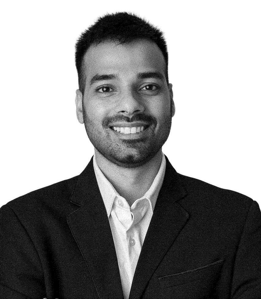 Smiling man with short hair wearing a dark blazer and light-colored shirt against a black background.