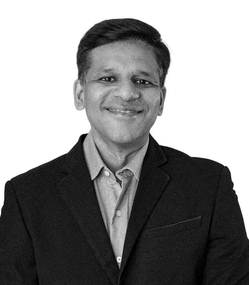 Man with short hair smiling, wearing a dark blazer over a buttoned shirt, against a transparent background.